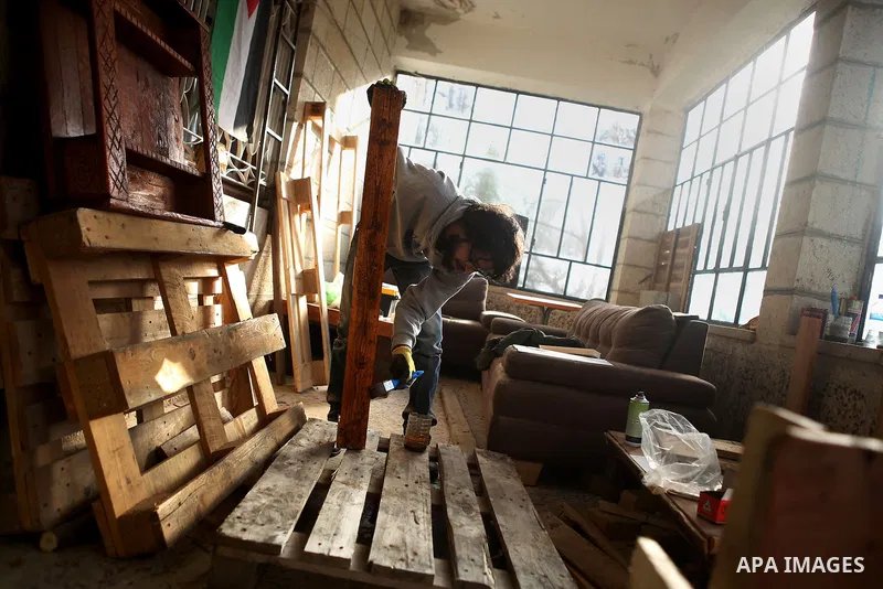 Azad Shams, a 25-year-old Palestinian artist, works at his workshop, in the West Bank city of Ramallah, February 25, 2015. Shams works with used wood boards and pieces to make artistic and creative furniture. Photo by Sh...
