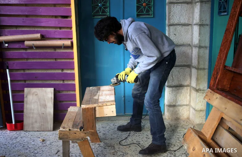 Azad Shams, a 25-year-old Palestinian artist, works at his workshop, in the West Bank city of Ramallah, February 25, 2015. Shams works with used wood boards and pieces to make artistic and creative furniture. Photo by Sh...
