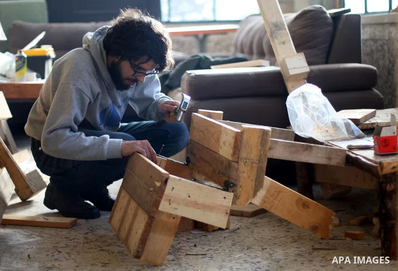 Azad Shams, a 25-year-old Palestinian artist, works at his workshop, in the West Bank city of Ramallah, February 25, 2015. Shams works with used wood boards and pieces to make artistic and creative furniture. Photo by Sh...