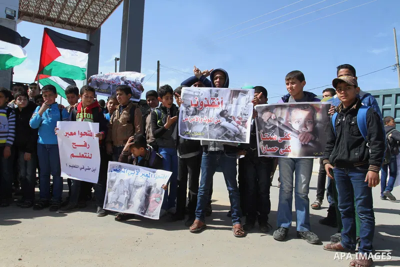 Palestinian students hold banners during a protest outside the Rafah crossing border, demanding the Egyptian authorities for the opening of the crossing, in Rafah in the southern Gaza Strip, February 26, 2015. Photo by A...