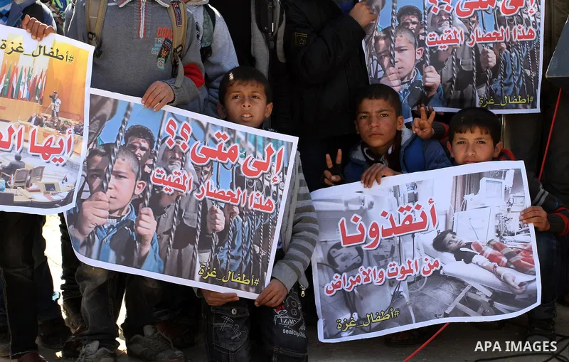 Palestinian students hold banners during a protest outside the Rafah crossing border, demanding the Egyptian authorities for the opening of the crossing, in Rafah in the southern Gaza Strip, February 26, 2015. Photo by A...