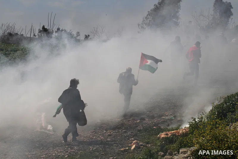 Palestinian protesters run for cover from tear gas fired by Israeli security forces during clashes in the West Bank village of Azzun, following a protest against the closure of the main road in the village, near the West...