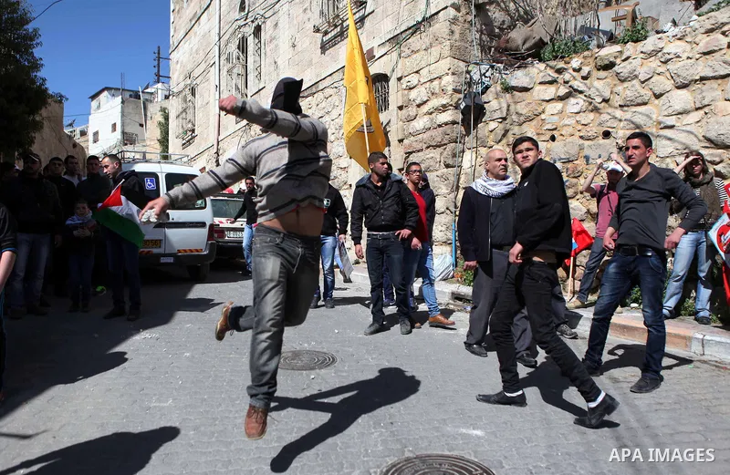 A Palestinian protester throws stones towards Israeli soldiers during clashes in a protest demanding the reopening of Shuhada Street in the West Bank city of Hebron on February 27, 2015. Photo by Mamoun Wazwaz