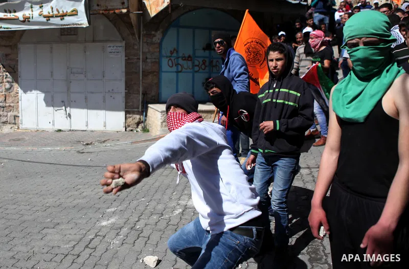 A Palestinian protester throws stones towards Israeli soldiers during clashes in a protest demanding the reopening of Shuhada Street in the West Bank city of Hebron on February 27, 2015. Photo by Mamoun Wazwaz