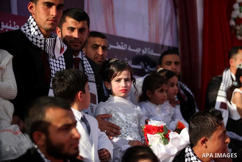 Palestinian grooms are accompanied by their sisters during a mass wedding ceremony in Gaza City, February 27, 2015. 50 couples took part in the mass wedding aided by Qatar. Photo by Ashraf Amra