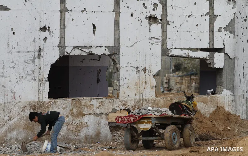 A Palestinian worker collects iron bars and stones from the rubbles of houses that witnesses said were destroyed by Israeli shelling during the most recent conflict between Israel and Hamas, to be recycled and reuse in c...
