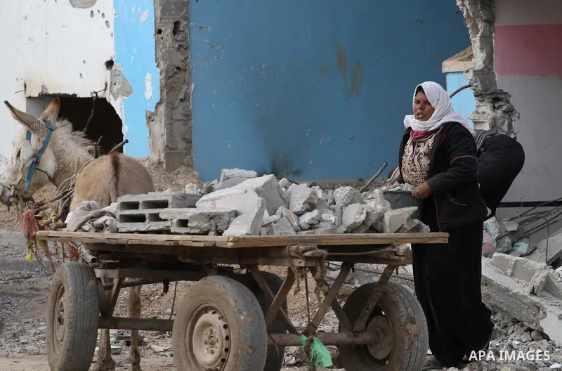 A Palestinian woman collects iron bars and stones from the rubbles of houses that witnesses said were destroyed by Israeli shelling during the most recent conflict between Israel and Hamas, to be recycled and reuse in co...