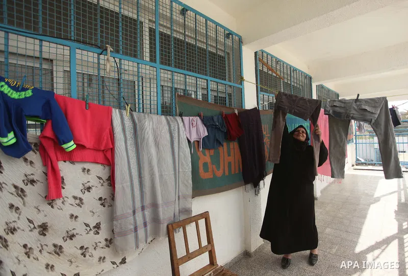 A Palestinian woman hangs laundry at a UN-run school in Gaza City where she is taking shelter at Beit Hanoun School in the northern Gaza Strip February 28, 2015. More than 100,000 homes in the Gaza Strip were damaged or...