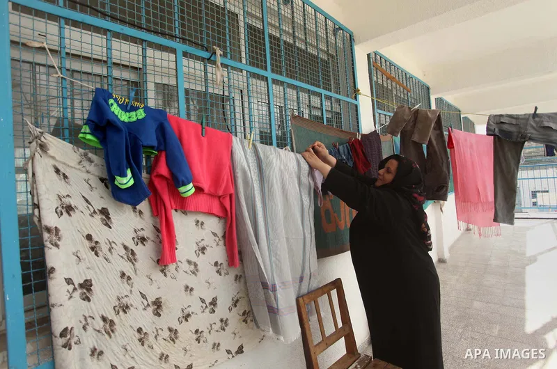 A Palestinian woman hangs laundry at a UN-run school in Gaza City where she is taking shelter at Beit Hanoun School in the northern Gaza Strip February 28, 2015. More than 100,000 homes in the Gaza Strip were damaged or...