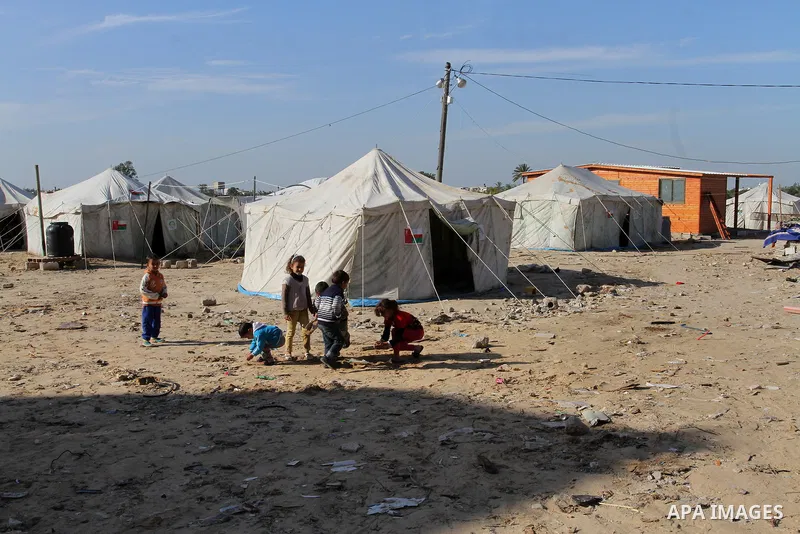 Palestinian children play outside their tents donated by a charity organisation as temporary housing for those whose houses were destroyed during a seven-week Israeli offensive, in Khuzaa, east of Khan Younis, in the sou...