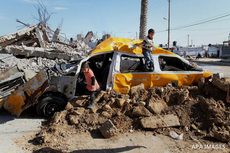 Palestinian children play on a destroyed car, in Khuzaa, east of Khan Younis, in the southern Gaza Strip, on March 01, 2015. Photo by Abed Rahim Khatib