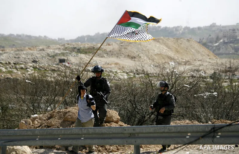 An Israeli border policeman removes a Palestinian flag during clashes with Palestinian protesters after they clear a protest on land that Palestinians say was confiscated by Israel for Jewish settlements, near the West B...