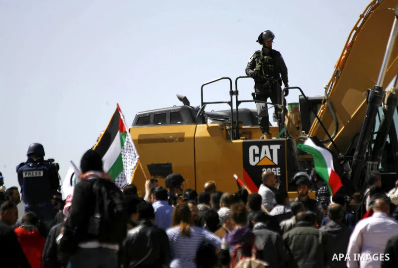 Palestinian protesters shout slogans in front of Israeli border policemen as they try to clear a protest on land that Palestinians say was confiscated by Israel for Jewish settlements, near the West Bank town of Abu Dis...