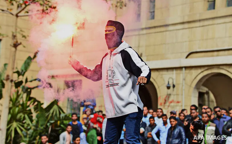 An Egyptian student who is support ousted President Mohamed Morsi and the Muslim Brotherhood light up flares as he takes part a protest against the military rule, in Cairo University on March 8, 2015. Photo by Amr Sayed