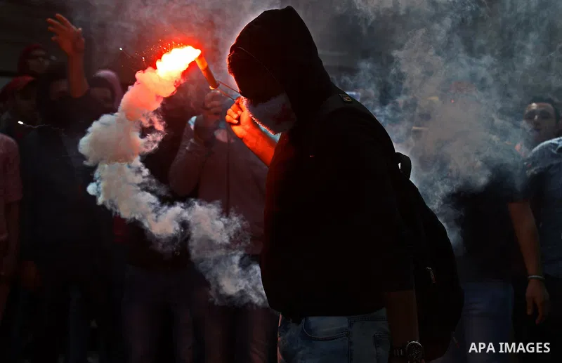 An Egyptian student who is support ousted President Mohamed Morsi and the Muslim Brotherhood light up flares as he takes part a protest against the military rule, in Cairo University on March 8, 2015. Photo by Amr Sayed