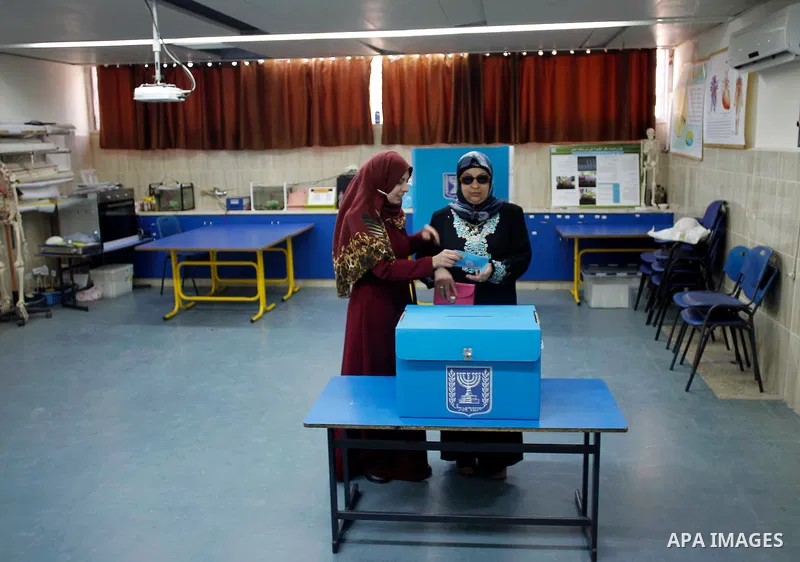 An Arab Israeli woman helps a blind woman to cast her ballot at a polling station in the northern Israeli town of Umm al-Fahm on March 17, 2015. Voting polls opened for unpredictable elections to determine whether Israel...