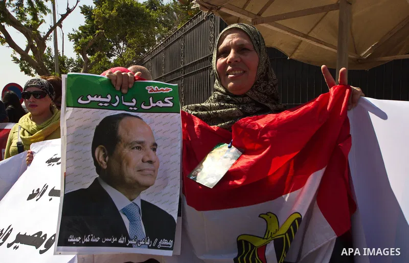 An Egyptian woman holds banners during a rally to support the Egyptian army and President Abdel Fattah al-Sisi, outside the Arab League headquarters, in Cairo on March 18, 2015. Photo by Amr Sayed