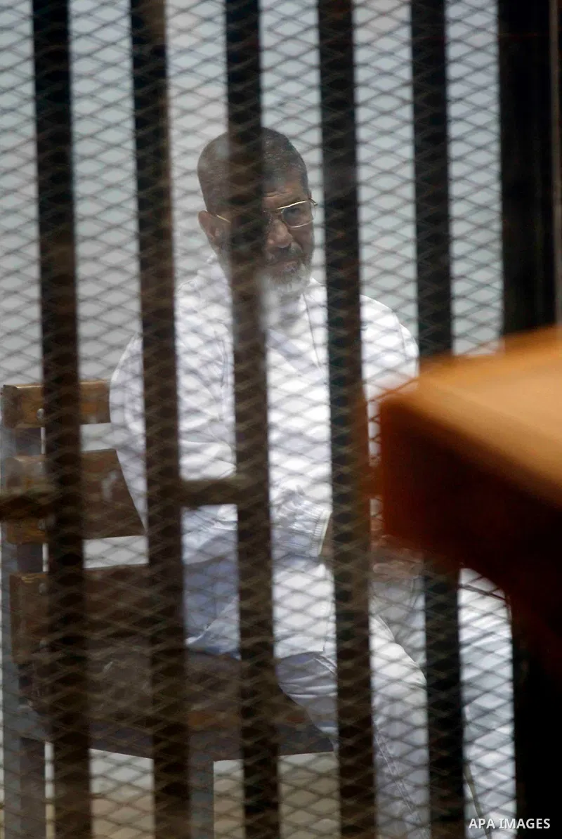 Egypt's deposed Islamist president Mohamed Morsi, is seen behind bars during his trial in a case of the "communicating with Qatar" at the court, in Cairo, on March 26, 2015. The session was held Wednesday to unseal the e...