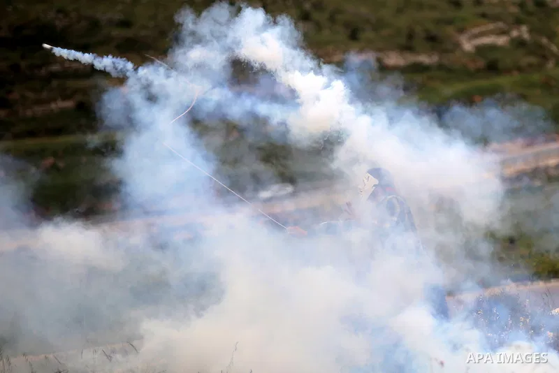 A Palestinian protester uses a sling shot to throw back a tear gas canister fired by Israeli security forces during clashes following a protest marking the Palestinian Land Day in the West Bank village of Nabi Saleh near...