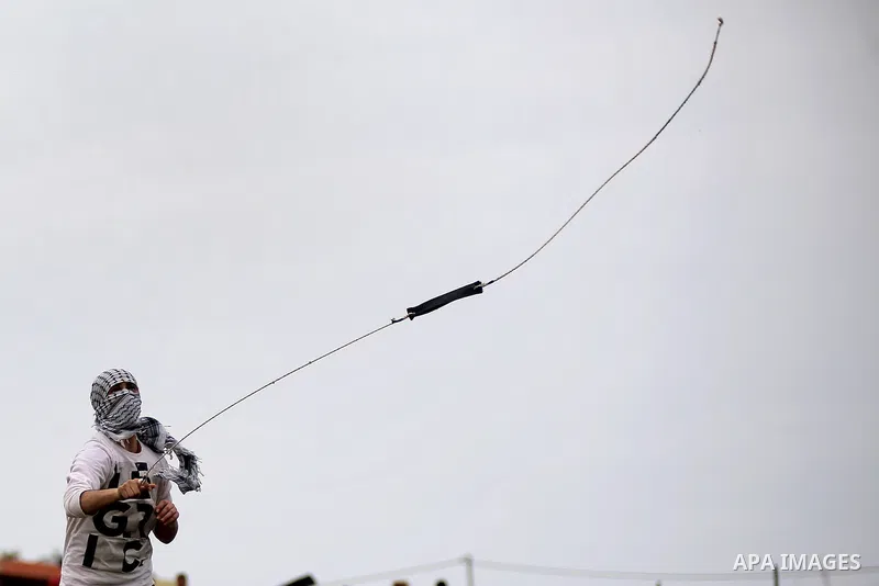 A Palestinian protester uses a sling shot to throw stones towards Israeli security forces during clashes following a protest marking the Palestinian Land Day in the West Bank village of Nabi Saleh near Ramallah, March 28...
