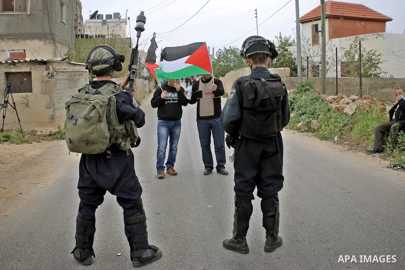 Palestinian protesters wave their national flag in front of Israeli security forces during a protest marking the Palestinian Land Day in the West Bank village of Nabi Saleh near Ramallah, March 28, 2015. Land Day commemo...