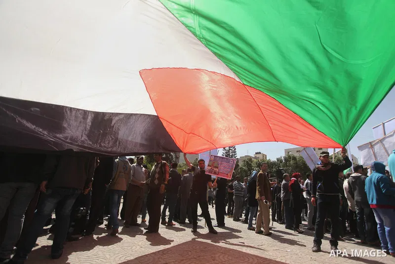 Protesters wave a Palestinian flag during a rally marking Land Day in Gaza City March 30, 2015.The annual demonstrations mark the deaths of six Arab Israeli protesters at the hands of Israeli police and troops during mas...