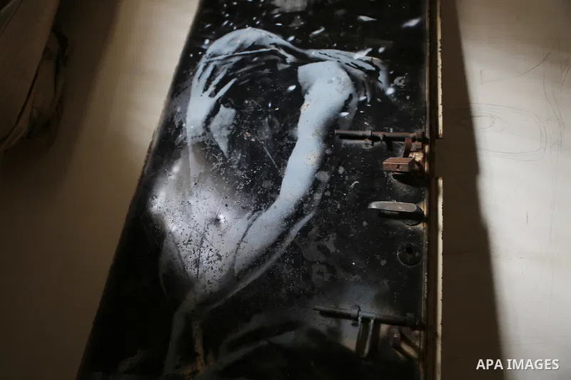 A picture taken in Khan Yunis, in the southern Gaza Strip on April 2, 2015, shows a mural of a weeping woman, said to have been painted by British street artist Banksy, on the door of a house that was destroyed during th...