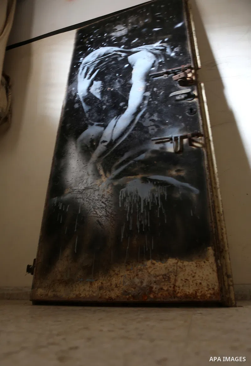 A picture taken in Khan Yunis, in the southern Gaza Strip on April 2, 2015, shows a mural of a weeping woman, said to have been painted by British street artist Banksy, on the door of a house that was destroyed during th...