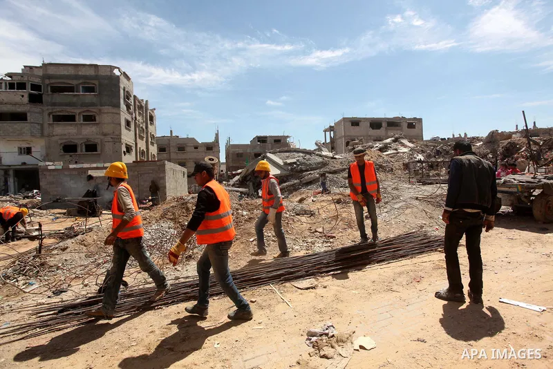 Palestinian laborers work in front of the rubble of buildings that were destroyed during the 50-day Israeli war on Gaza Strip in the summer of 2014, in Gaza City's al-Shejaiya neighbourhood, on April 2, 2015. The Palesti...