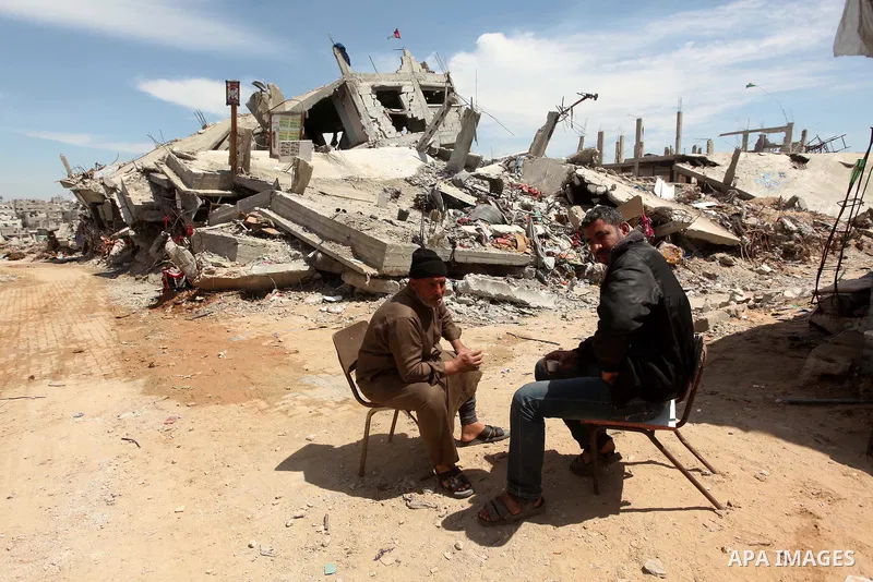 Palestinians sit in front on the rubble of their house that was destroyed during the 50-day Israeli war on Gaza Strip in the summer of 2014, in Gaza City's al-Shejaiya neighbourhood, on April 2, 2015. The Palestinians fo...