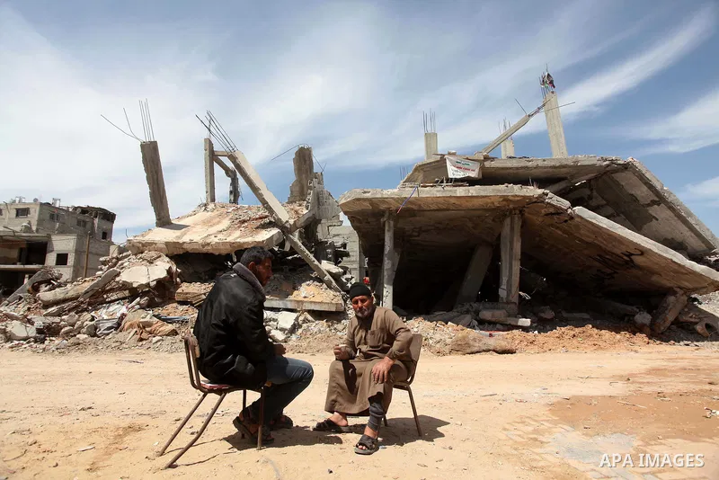 Palestinians sit in front on the rubble of their house that was destroyed during the 50-day Israeli war on Gaza Strip in the summer of 2014, in Gaza City's al-Shejaiya neighbourhood, on April 2, 2015. The Palestinians fo...