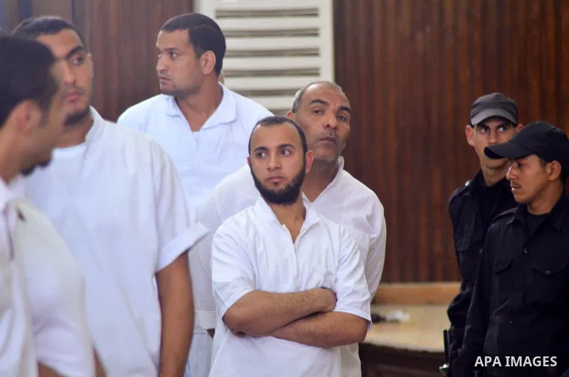 Egyptian defendants in the trial of US embassy violence stand in the court room during their trial in Cairo on April 2, 2015. The Cairo Criminal Court delayed the trial of 23 of members of Muslim Brotherhood accusing in...