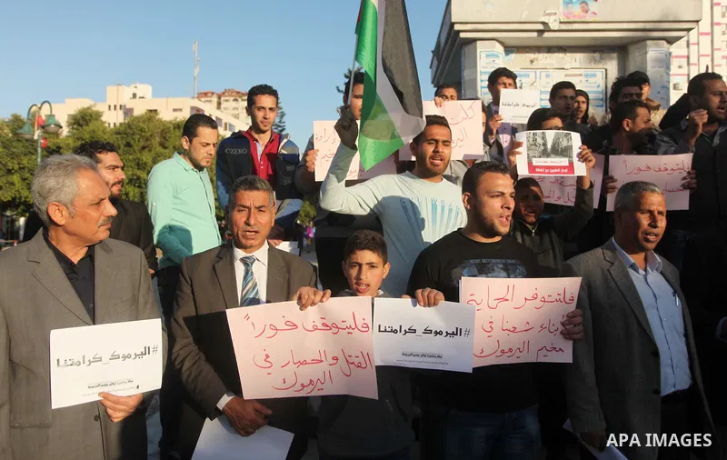 Palestinians shout slogans as they hold banners during a gathering in solidarity with the Palestinians living in Syria's Yarmouk camp, which is besieged by government forces and has been largely overrun by jihadist fight...