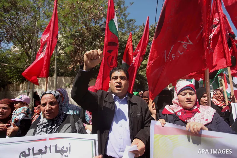 Palestinian supporters of the Democratic Front for the Liberation of Palestine (DFLP), shout slogans as they hold banners during a gathering in solidarity with the Palestinians living in Syria's Yarmouk camp, which is be...