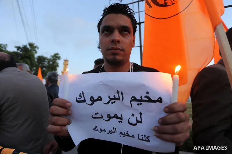 Palestinians light candles as they hold banners during a rally in solidarity with the Palestinians living in Syria's Yarmouk camp, which is besieged by government forces and has been largely overrun by jihadist fighters,...