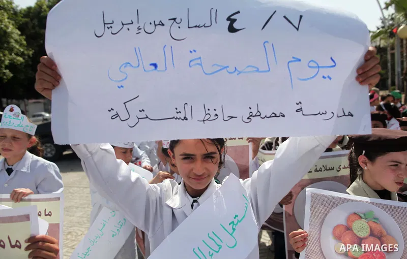 Palestinian students hold banners during a rally to mark the World Health Day, in Gaza city on April 7, 2015. Photo by Ashraf Amra