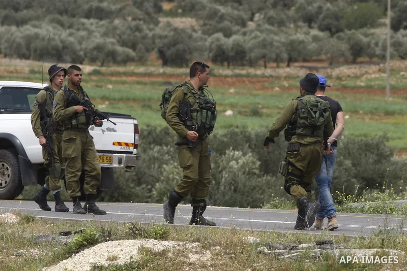 A Palestinian onlooker is detained by an Israeli soldier, following an argument with Israeli soldiers, while watching the scene of a stabbing attack near the entrance to the Shilo settlement on route 60, the main road li...