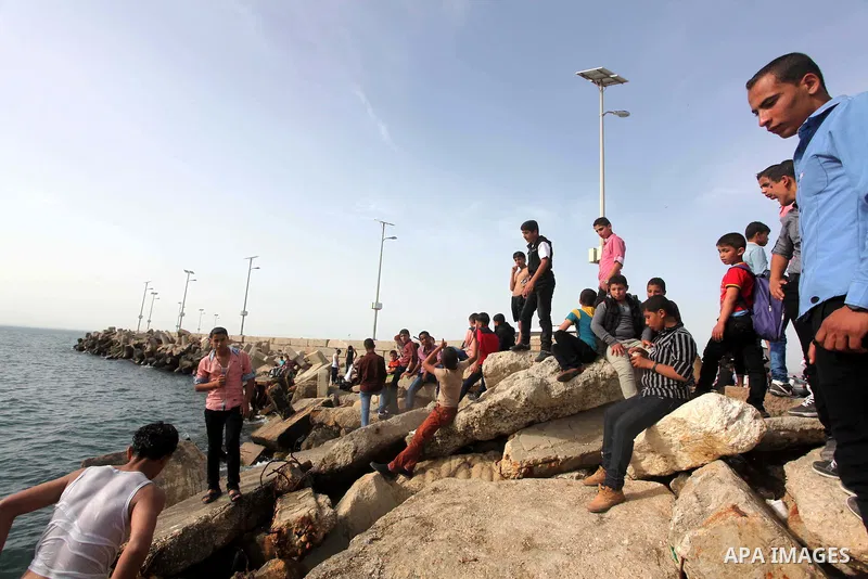 Palestinians sit on the beach as they enjoy a warm day at the seaport in Gaza City on April 8, 2015. Photo by Ashraf Amra