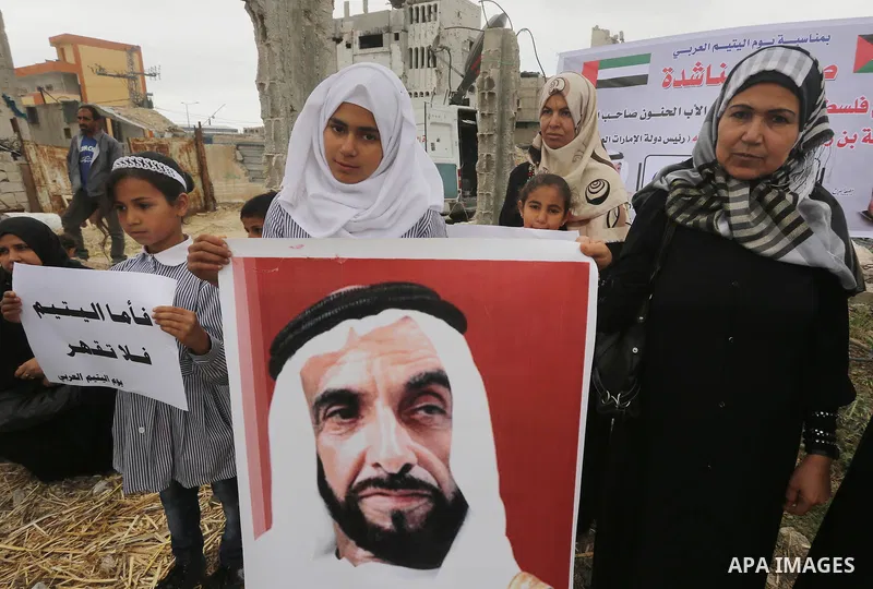 Relatives of Palestinian orphans hold banners during a protest against stop the payment of orphans aid in front of the rubbles of houses were destroyed during a seven-week Israeli offensive, in the east of Gaza City, on...