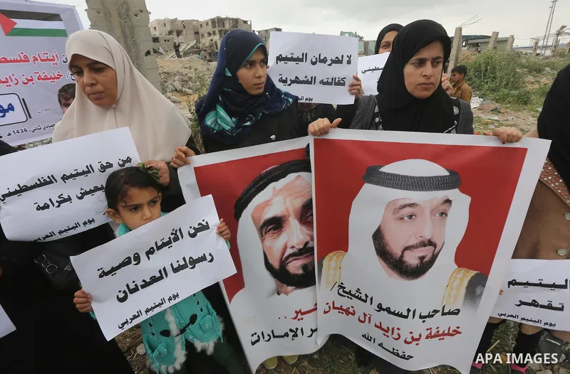 Relatives of Palestinian orphans hold banners during a protest against stop the payment of orphans aid in front of the rubbles of houses were destroyed during a seven-week Israeli offensive, in the east of Gaza City, on...