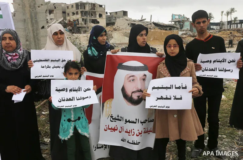 Relatives of Palestinian orphans hold banners during a protest against stop the payment of orphans aid in front of the rubbles of houses were destroyed during a seven-week Israeli offensive, in the east of Gaza City, on...