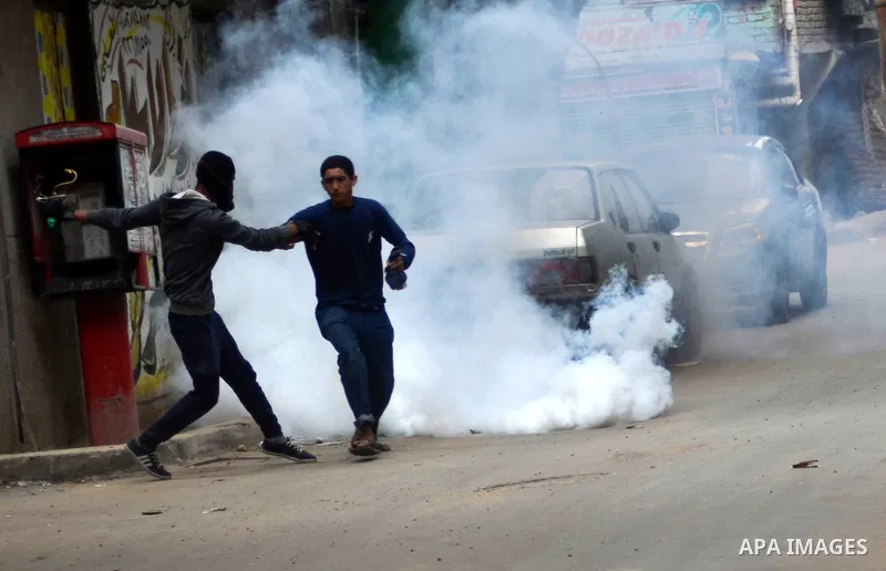 Egyptians run for cover from tear gas fired by riot police during clashes with supporters of Muslim Brotherhood and ousted president Mohammed Morsi following a protest against military rule in al-Matariya district, near...