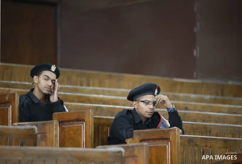 Egyptian Policemen sit in front of empty bars during the trial of Muslim brotherhood leaders in Cairo, April 11, 2015. An Egyptian court sentenced Mohamed Badie, the leader of the outlawed Muslim Brotherhood, and 13 othe...