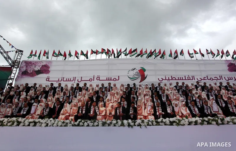 Palestinian grooms sit with their brides on the stage during a mass wedding ceremony in Gaza City, on April 11, 2015. Nearly 200 Palestinian couples were married in a ceremony funded by an Emirati governmental organisati...