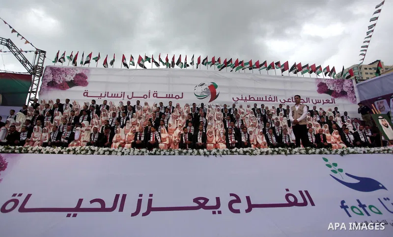 Palestinian grooms sit with their brides on the stage during a mass wedding ceremony in Gaza City, on April 11, 2015. Nearly 200 Palestinian couples were married in a ceremony funded by an Emirati governmental organisati...