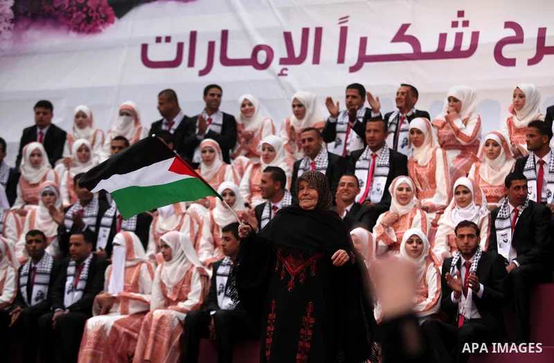 A Palestinian woman waves her national flag during a mass wedding ceremony in Gaza City, on April 11, 2015. Nearly 200 Palestinian couples were married in a ceremony funded by an Emirati governmental organisation. Photo...