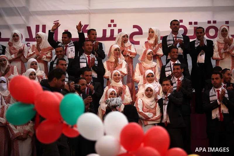 Palestinian grooms sit with their brides on the stage during a mass wedding ceremony in Gaza City, on April 11, 2015. Nearly 200 Palestinian couples were married in a ceremony funded by an Emirati governmental organisati...