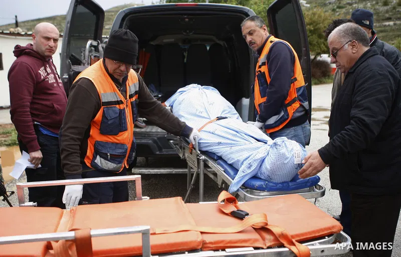 Palesinian midical workers carry the body of Mohammed Karara, into an ambulance afer delivered by Israeli forces near the entrance to the Shilo settlement on route 60, the main road linking the West Bank cities of Ramall...