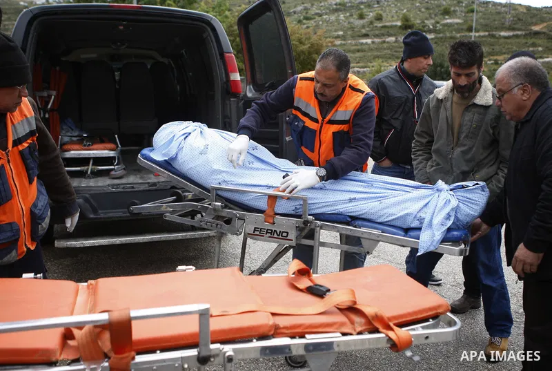Palesinian midical workers carry the body of Mohammed Karara, into an ambulance afer delivered by Israeli forces near the entrance to the Shilo settlement on route 60, the main road linking the West Bank cities of Ramall...