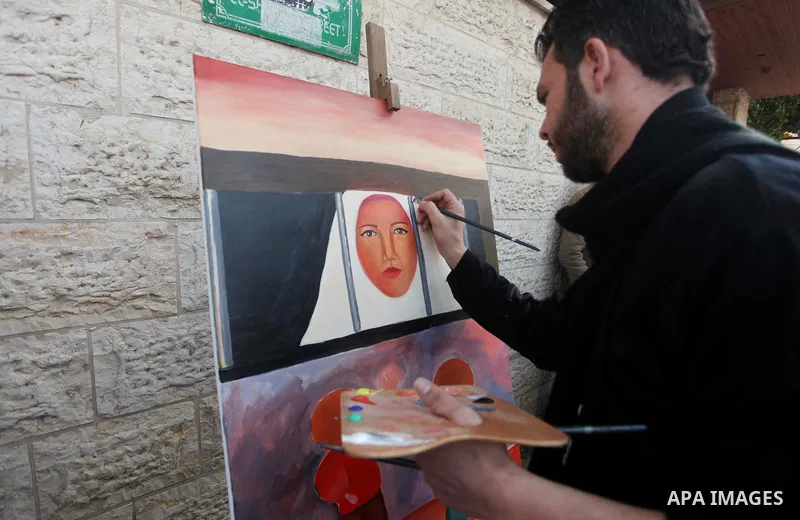 A Palestinians artist paints artwork during a protest calling for the release of Palestinian prisoners held in Israeli jails, outside the International Red Cross offices in Gaza City, on April 13, 2015. Photo by Ashraf A...
